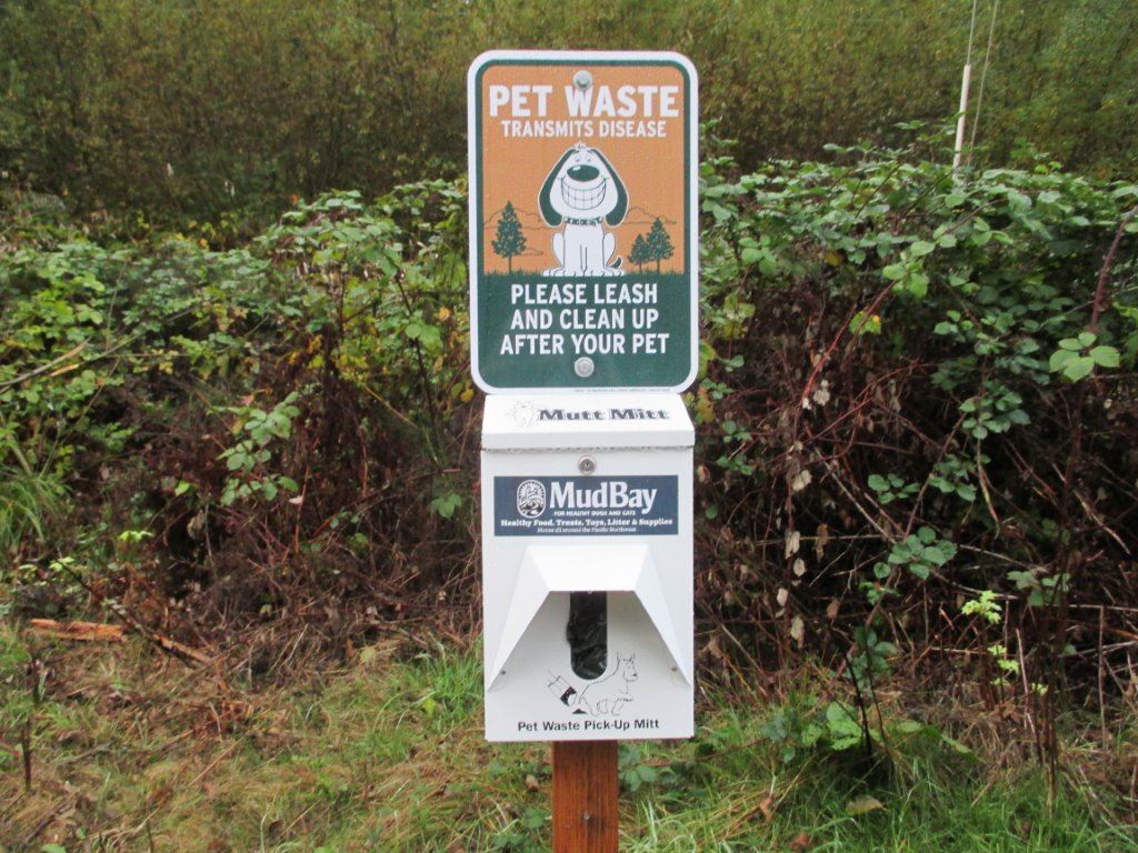 Plastic pet waste mitt dispenser with sign of a smiling dog